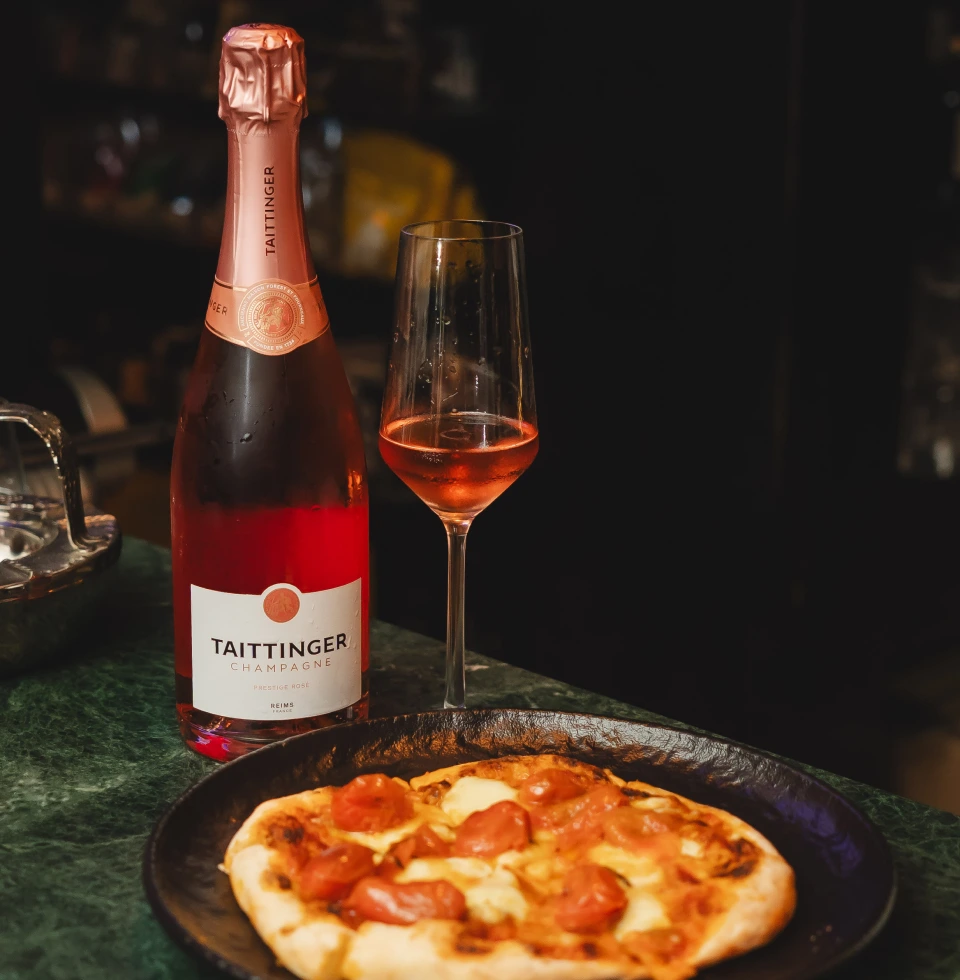 Pizza junto a copa y botella de champagne